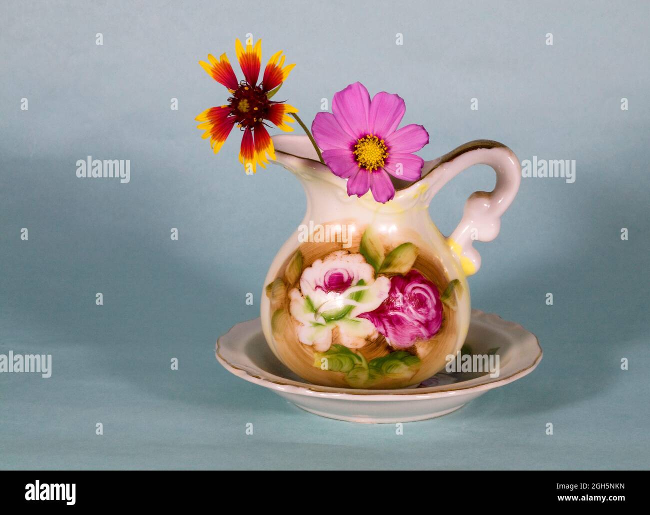 Ein zierlicher Strauß von bunten Gartenblumen in einer kleinen Vase auf einem schlichten Hintergrund. Stockfoto