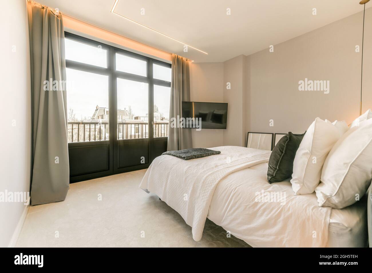 Innenraum des Schlafzimmers mit weichem Bett mit Kissen vor dem Fenster platziert Stockfoto