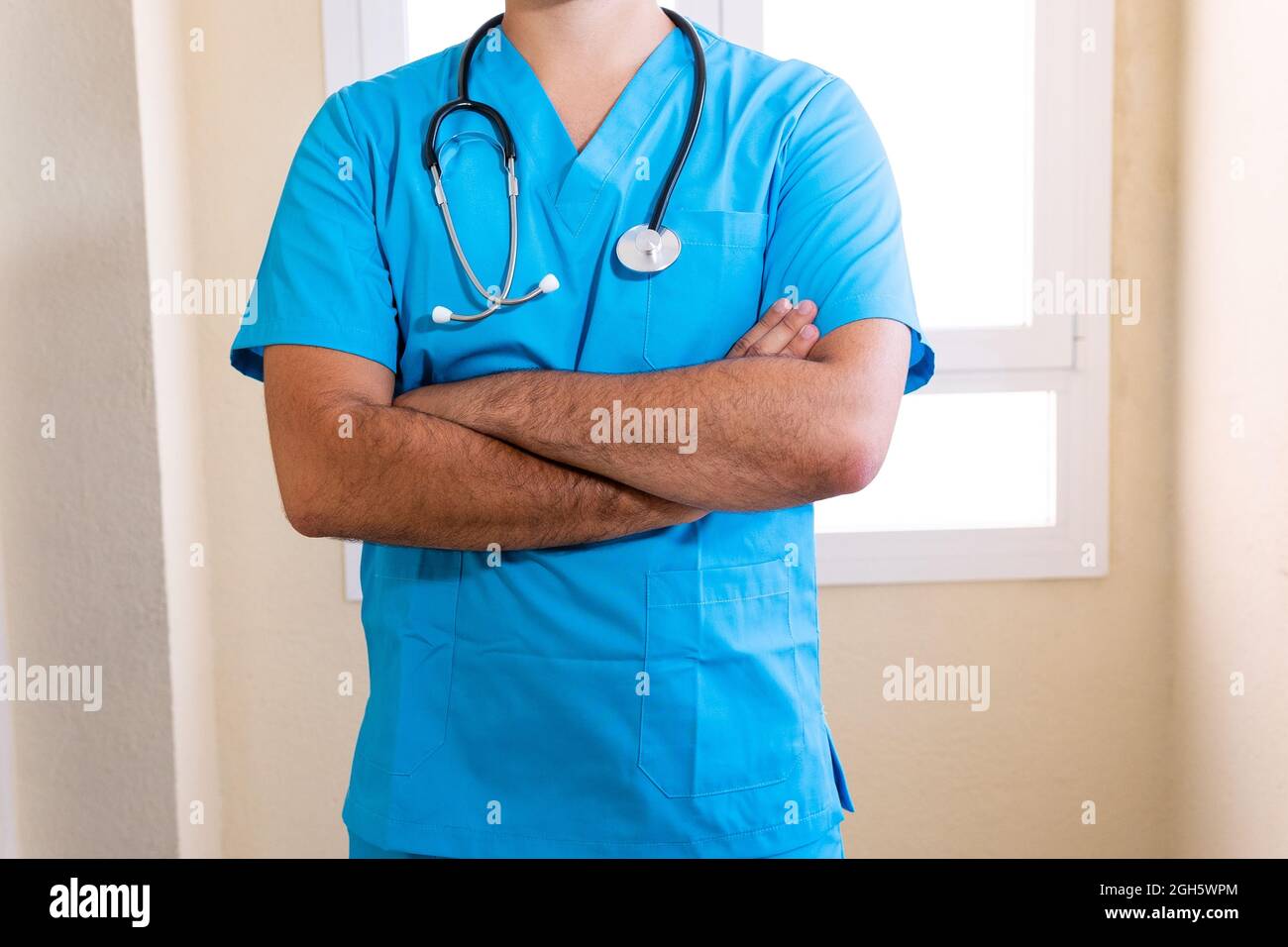 Crop anonyme männliche Medic in blauer Uniform und mit Stethoskop in der Klinik stehen Stockfoto