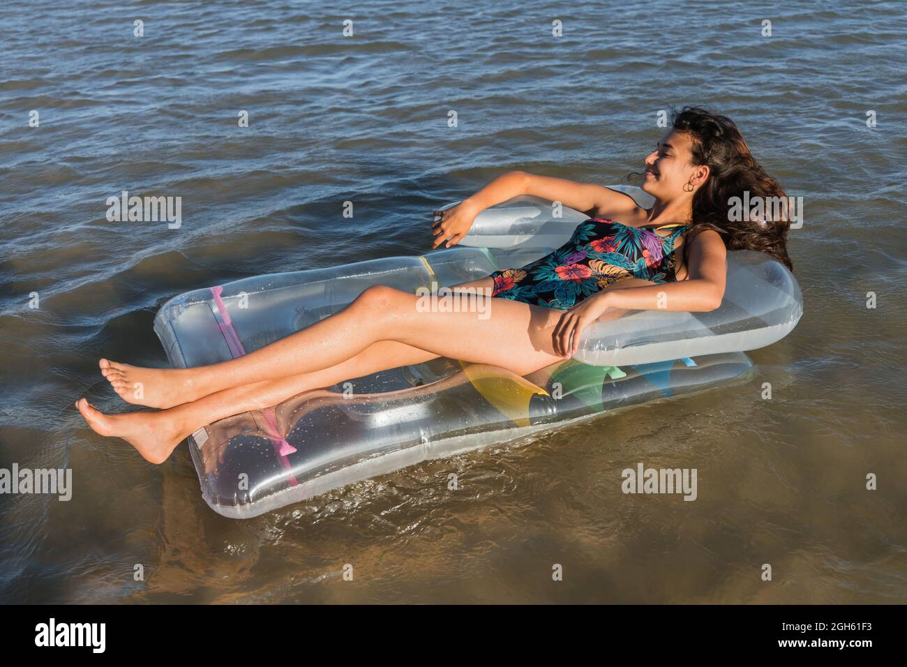 Inhalt Frau, die auf einer aufblasbaren Matratze liegt und an sonnigen Sommertagen auf dem Meerwasser schwimmt und wegschaut Stockfoto