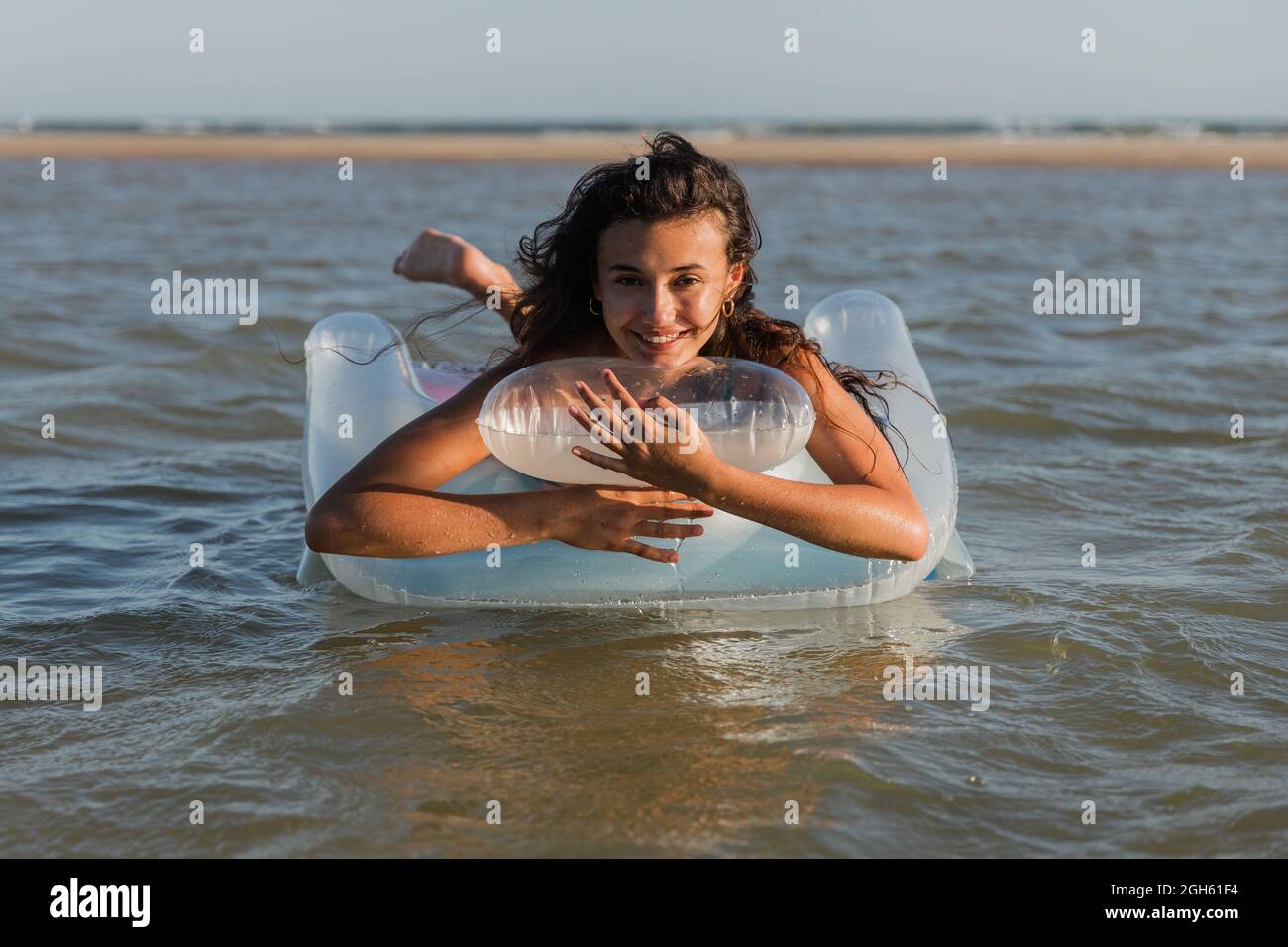 Inhalt Frau, die auf einer aufblasbaren Matratze liegt, schwimmt im Sommer an sonnigen Tagen auf dem Meerwasser und schaut in die Kamera Stockfoto