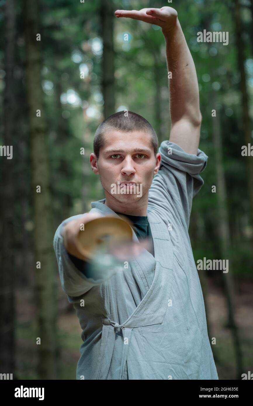 Traditionelle Kleidung übt während des Kung Fu-Trainings im Wald die Schwertschwerthaltung Stockfoto