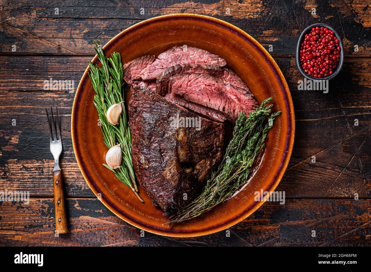 Gerösteter Aufhänger oder Onglet-Rinderfleischsteak in Scheiben auf einem rustikalen Teller mit Hackschnitzel. Dunkler Holzhintergrund. Draufsicht Stockfoto