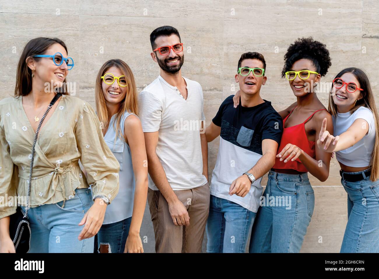 Fröhliche Menschen mit Brillen, die Spaß haben, an einer Wand zu lächeln Stockfoto