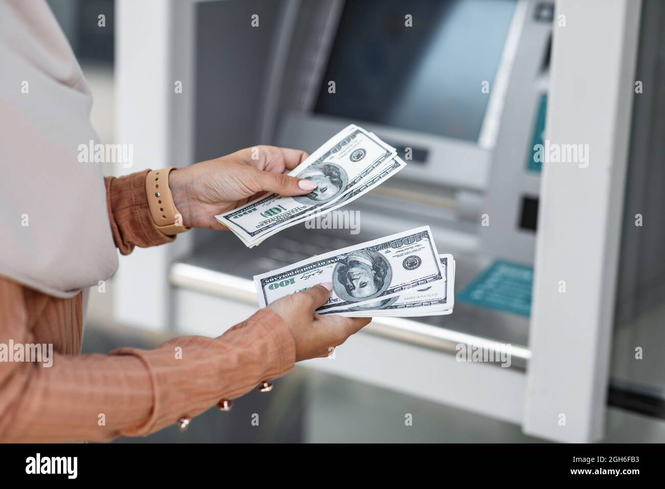 Eine zufriedene Dame hält Geldscheine in den Händen in der Nähe des Geldautomaten. Viel Glück. Geldautomaten Stockfoto