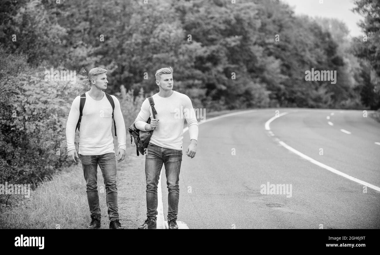 Gehen Sie in die Nähe des Stadtrandes. Reisende auf dem Weg. Freunde, die Wanderer auf Reisen anhalten. Unternehmen Freunde Reisende Anhalter auf Straße Natur Hintergrund. Beginnen Stockfoto