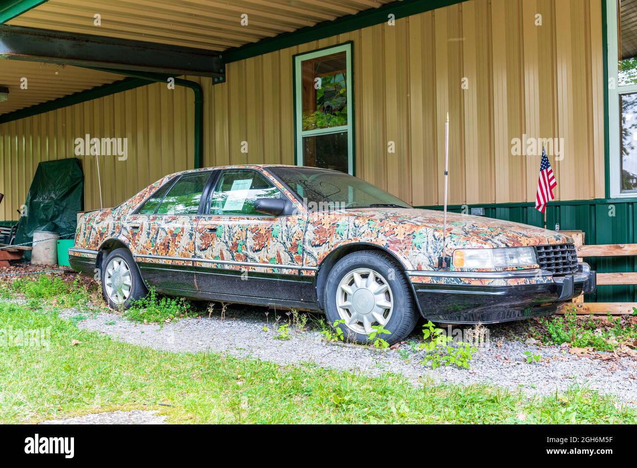 OLEAN, NY, USA-14 AUGUST 2021: 1996 Cadillac Sevilla 0mit Tarnfarbe, sitzend im Rock City Park, in der Nähe von Olean, NY. Stockfoto