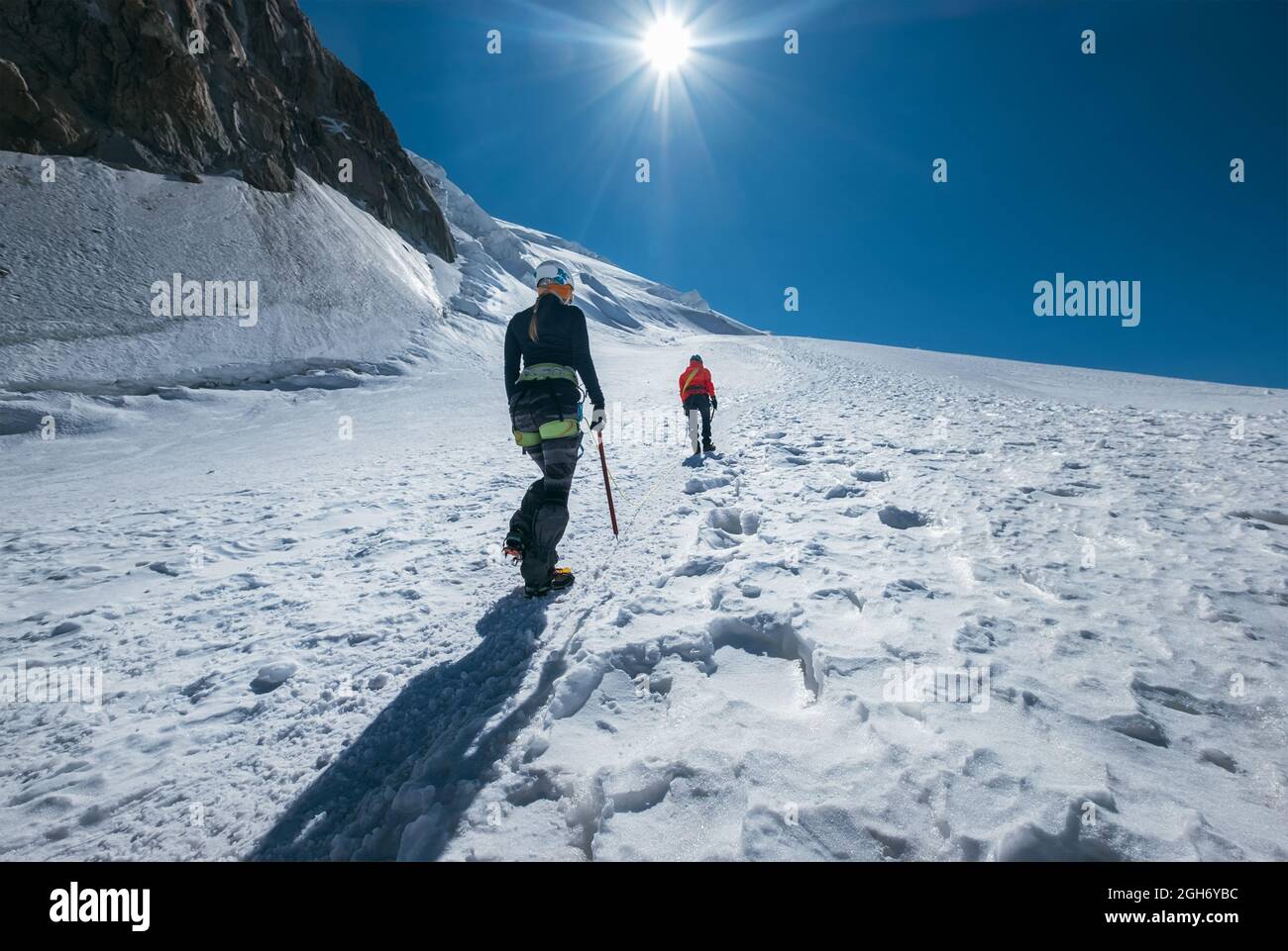 Zwei junge Frauen Seilschaft besteigen Mont Blanc (Monte Bianco) Gipfel 4,808 m gekleidete Bergsteigerbekleidung mit Eispickel beim Wandern an verschneiten Hängen. Peop Stockfoto