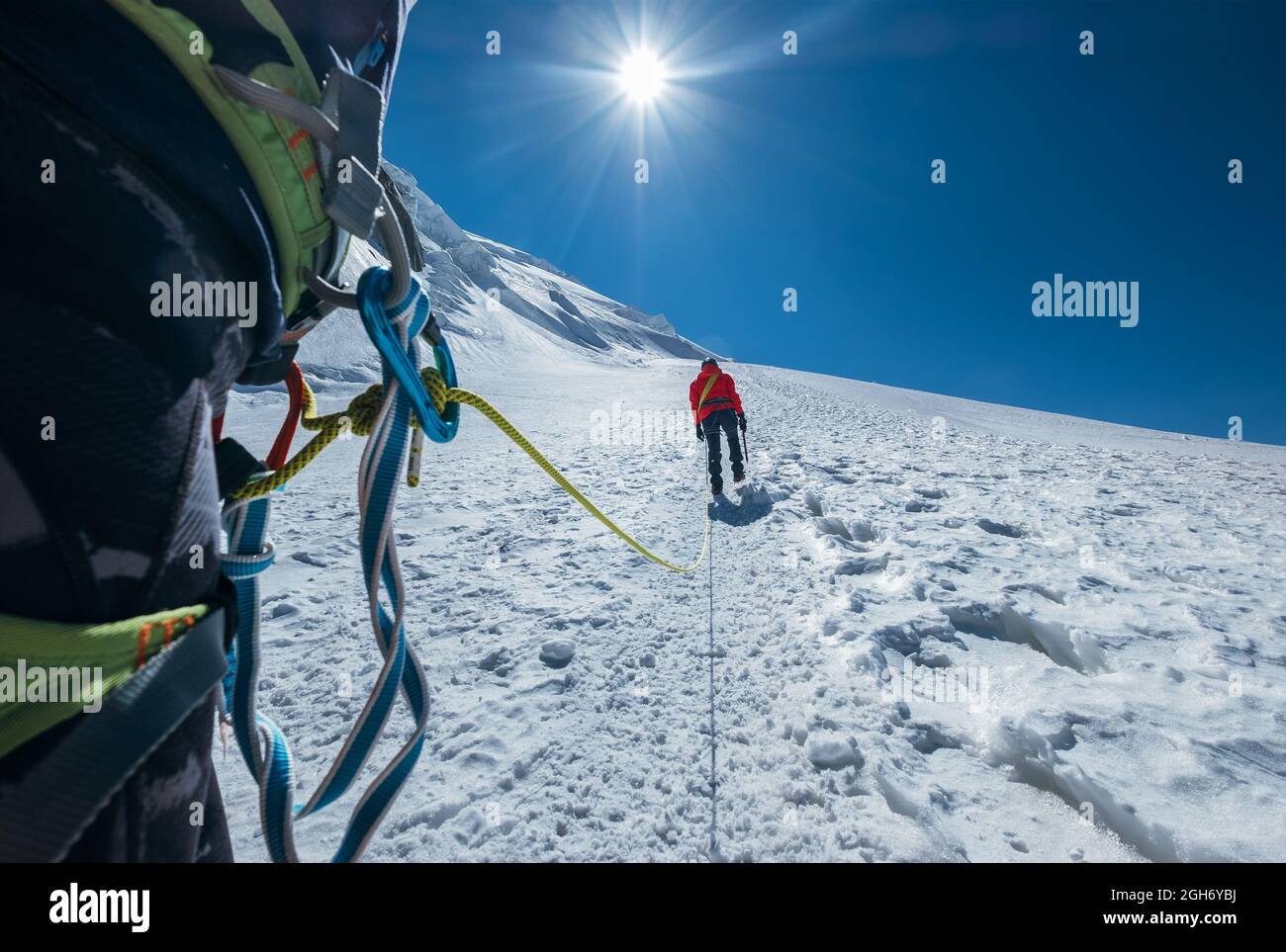Seilschaft beim Aufstieg zum Gipfel des Mont Blanc (Monte Bianco) 4,808m bekleidete rote Bergsteigerbekleidung Wandern an verschneiten Hängen mit Karabiner Klettergurt Stockfoto