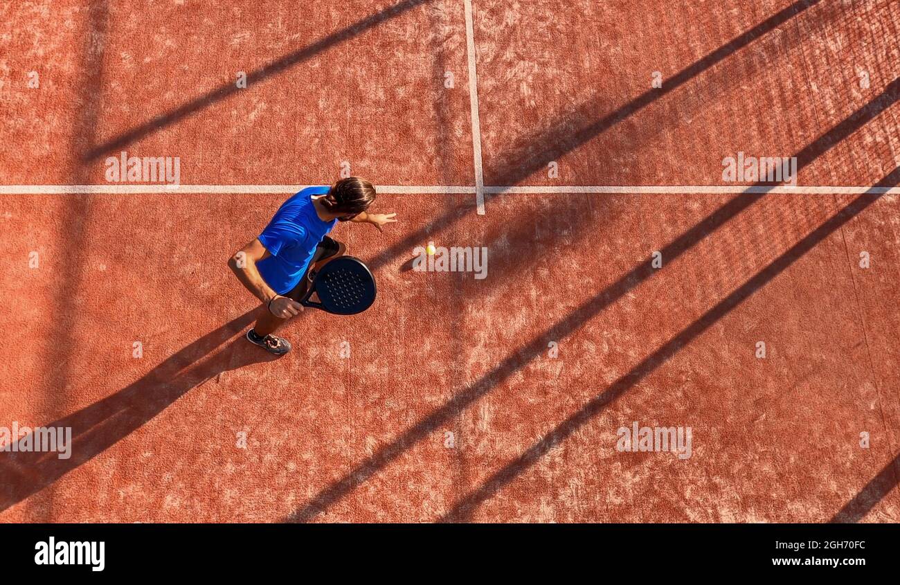 Draufsicht auf einen professionellen Paddle-Tennisspieler, der den Ball auf einem Platz im Freien dribbert. Stockfoto