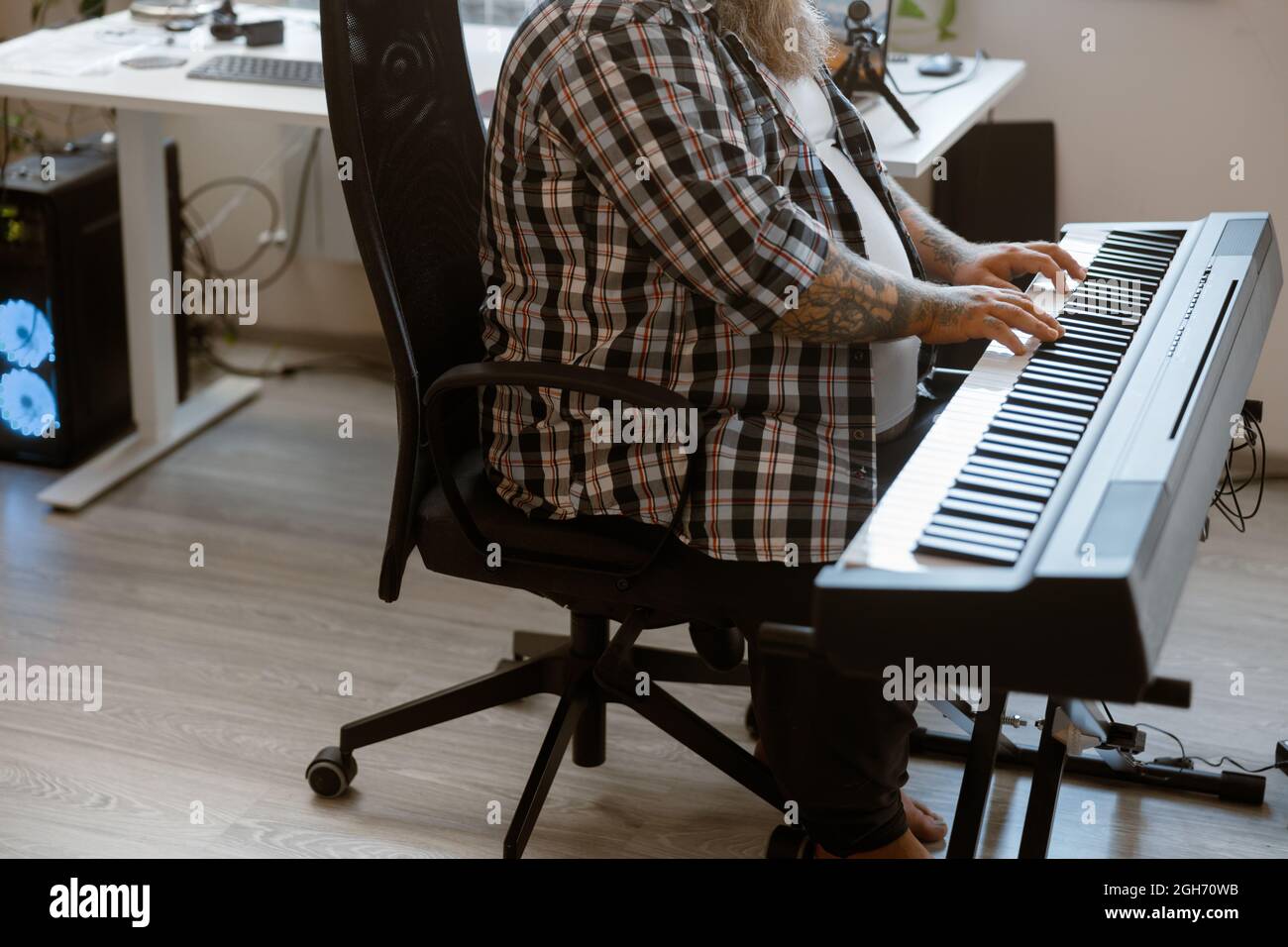 Ein talentierter Mann mit Übergewicht spielt im Heimstudio einen Sound-Synthesizer Stockfoto