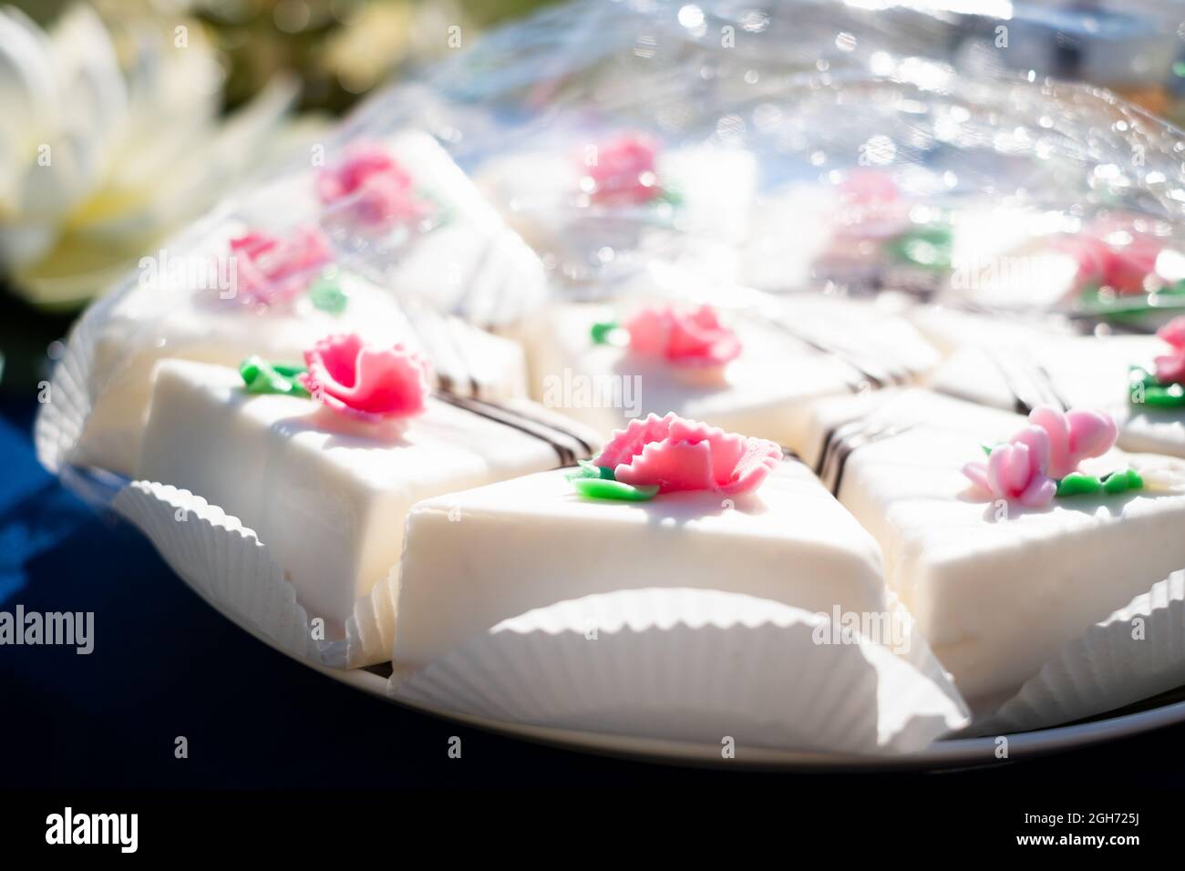 Süße Kuchenscheiben auf einem Teller. Weiße Marzipan-Tarte mit rosa Blumenschmuck. Stockfoto