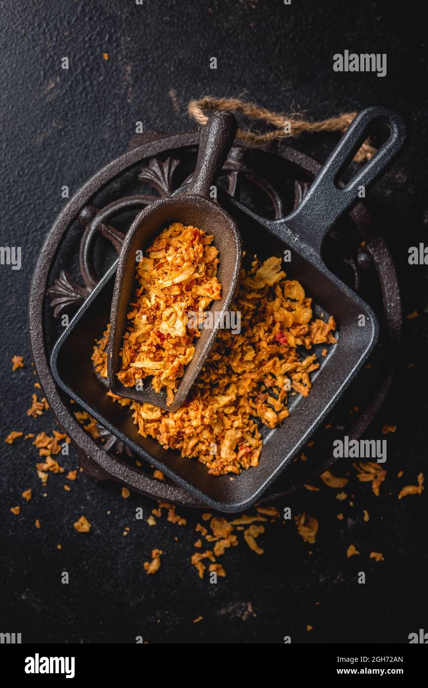 Hausgemachte gebratene Zwiebeln in eiserner Küchenschaufel mit schwarzer Pfanne auf schwarzem Hintergrund Stockfoto