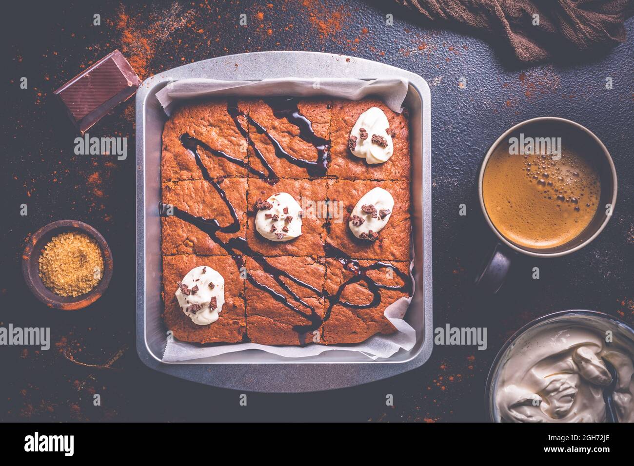 Hausgemachte Brownies mit einer Tasse Kaffee und Backzutaten auf braunem Hintergrund Stockfoto