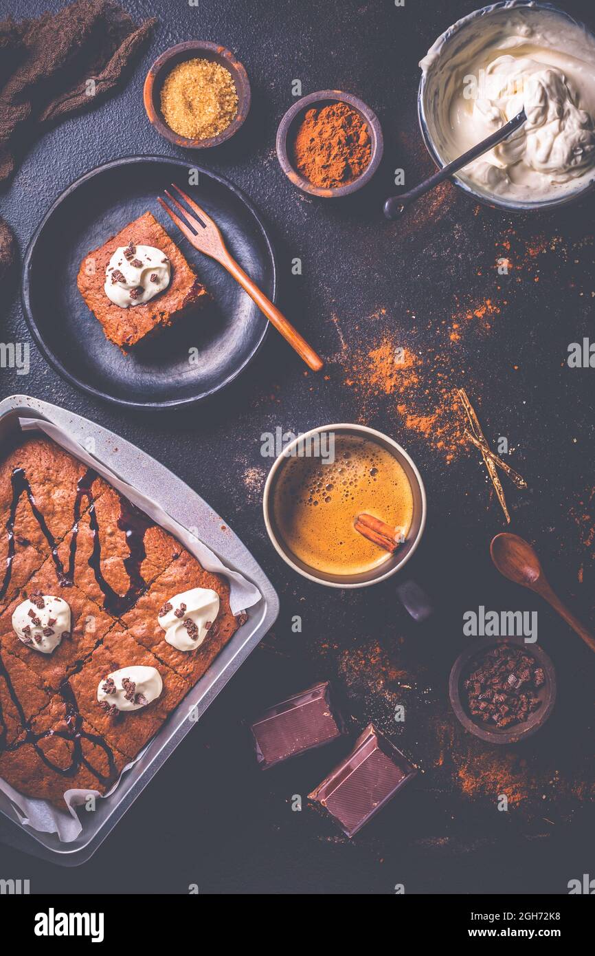 Hausgemachte Brownies mit einer Tasse Kaffee und Backzutaten auf braunem Hintergrund Stockfoto