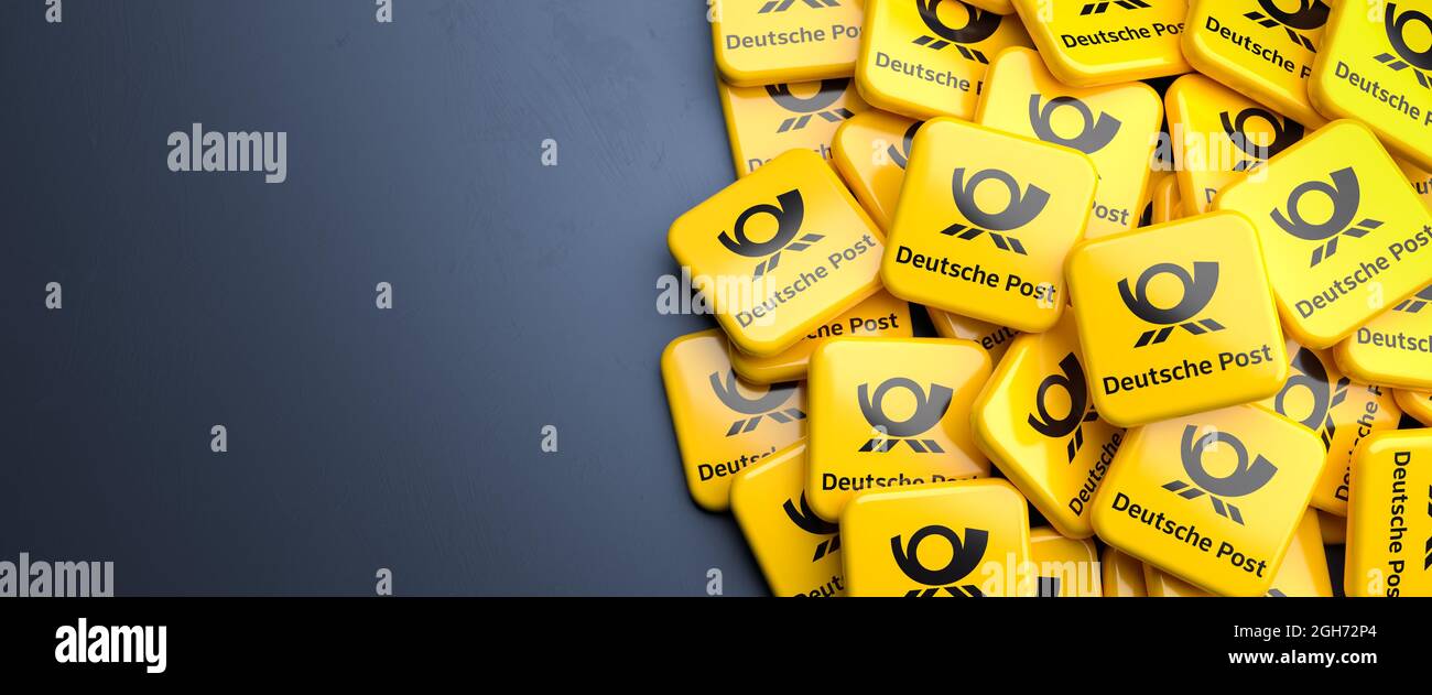 Logos der deutschen Paket- und Briefzustellungs- und Supply-Chain-Management-Gesellschaft Deutsche Post auf einem Haufen auf einem Tisch. Speicherplatz kopieren. Webbanner-Format. Stockfoto