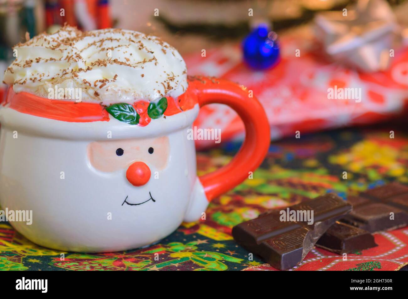Weihnachten heiße Schokolade in Santa Gesicht Becher mit Schlagsahne und rasierte Schokolade mit Schokolade Quadrate auf der Seite. Heißer Weihnachtsdrink. Weihnachten p Stockfoto