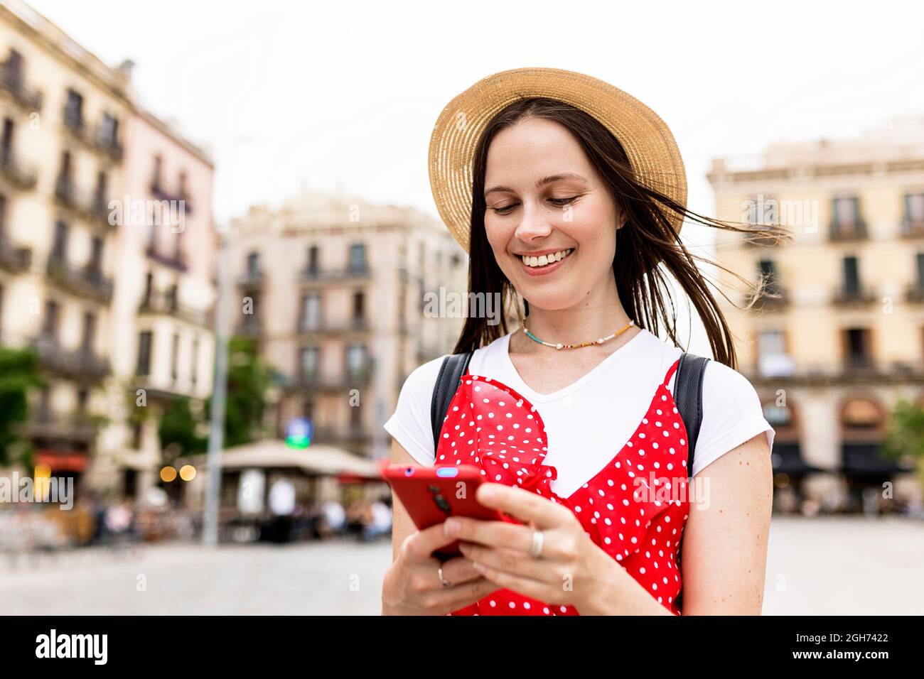 Junge Erwachsene Touristenfrau, die auf der Straße mit dem Mobiltelefon unterwegs ist Stockfoto
