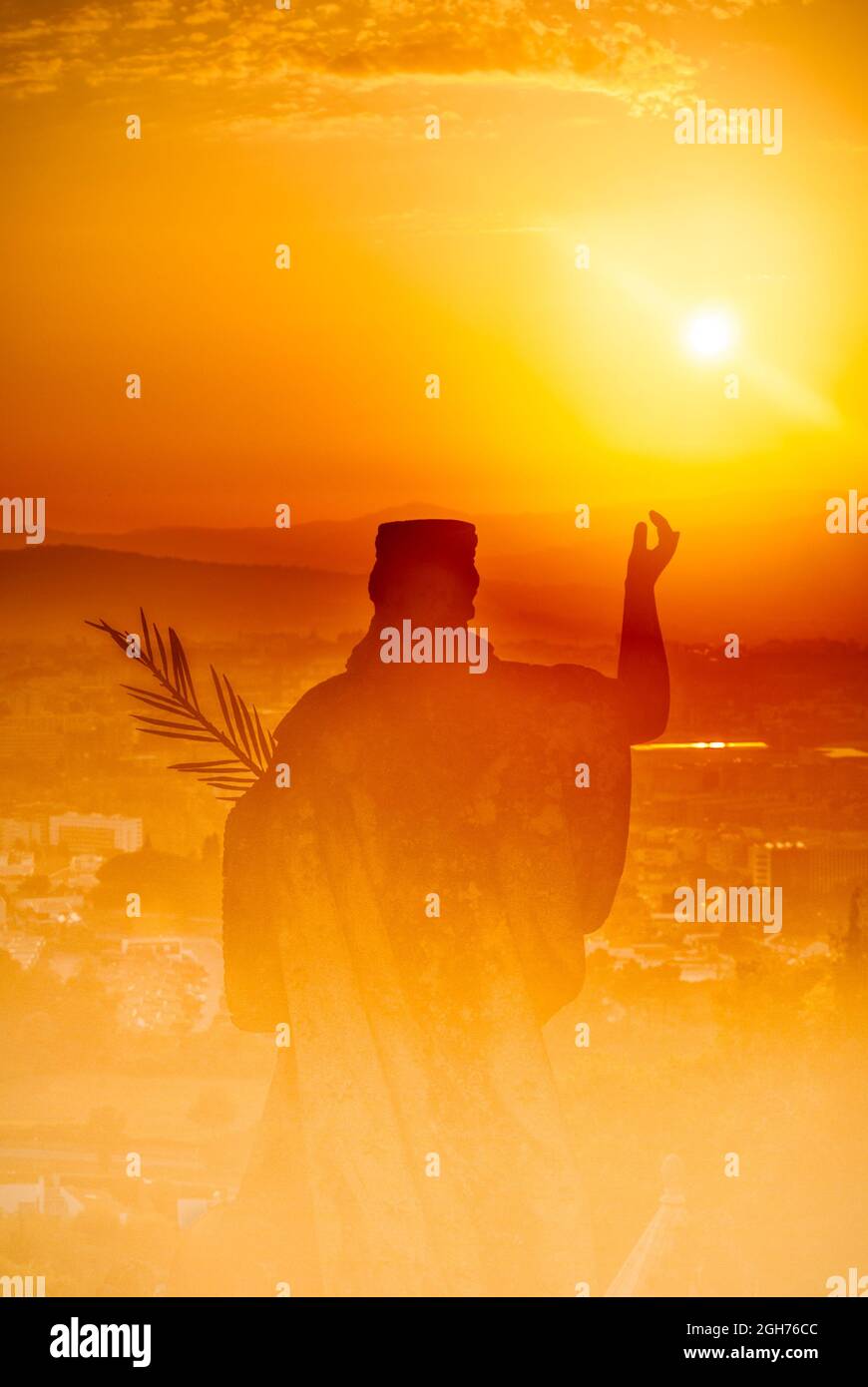Abstraktes Bild einer Statue bei Sonnenuntergang einer Frau mit einem Palmenzweig und einer Landschaft einer Stadt darunter, Symbol des Glaubens und des Friedens Stockfoto