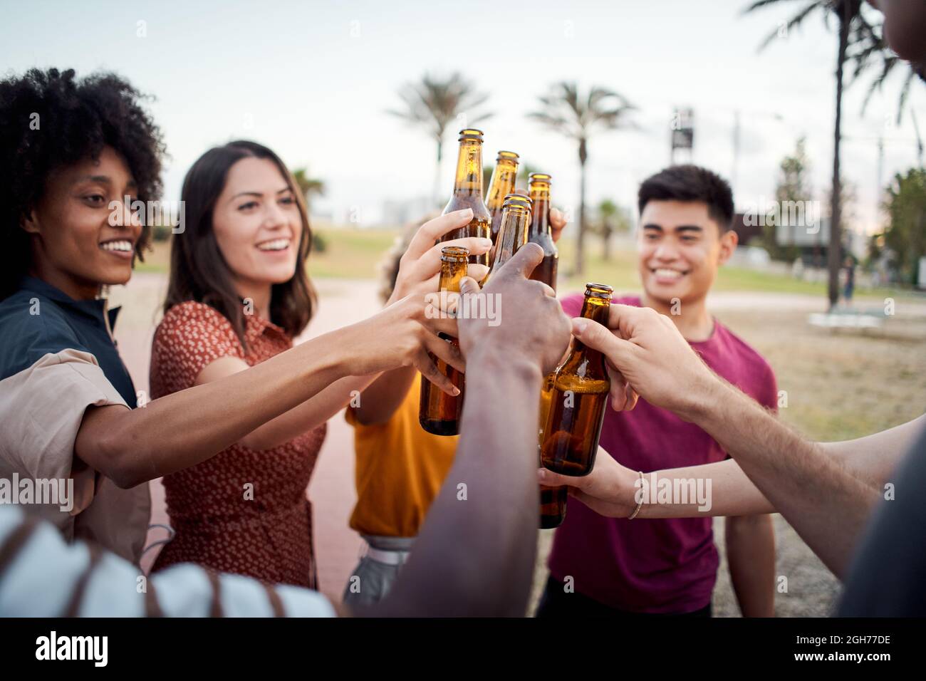 Nahaufnahme der Hände einer Gruppe junger Menschen verschiedener Rassen, die beim Sonnenuntergang fröhlich toben. Prost. Stockfoto