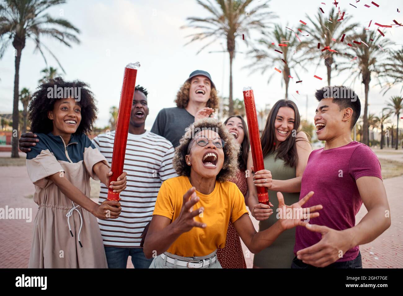Eine internationale Gruppe junger Menschen feiert draußen mit Konfetti. Konzept der Feier, Party, genießen, fröhlich. Stockfoto