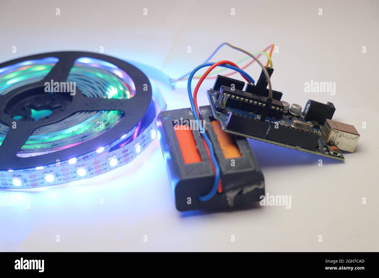 Arduino-Board steuert Streifen von LED-Licht, Batterie und Mikrocontroller Stromversorgung eines Streifens von RGB-LED auf einem Tisch gelegt Stockfoto