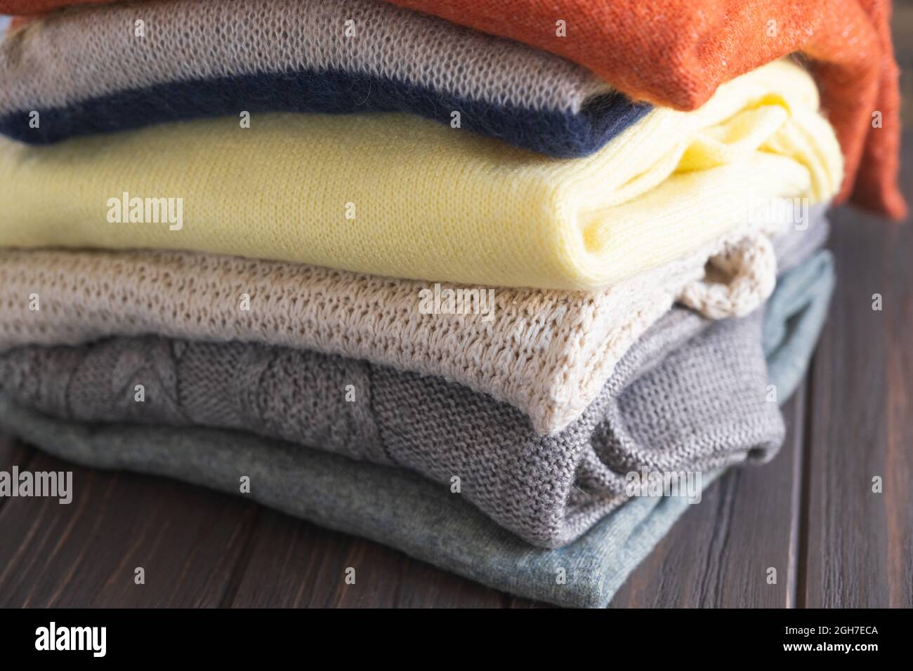 Kuschelige Pullover in Herbstfarben auf braunem Holzhintergrund. Stockfoto