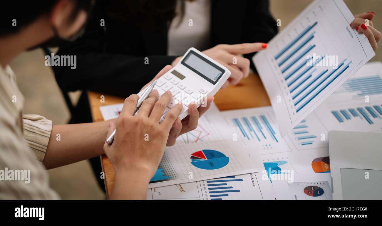 Das Geschäftsteam verwendet einen Rechner und einen Laptop, um die Zahlen auf seinem Schreibtisch in einem Büro zu berechnen. Stockfoto