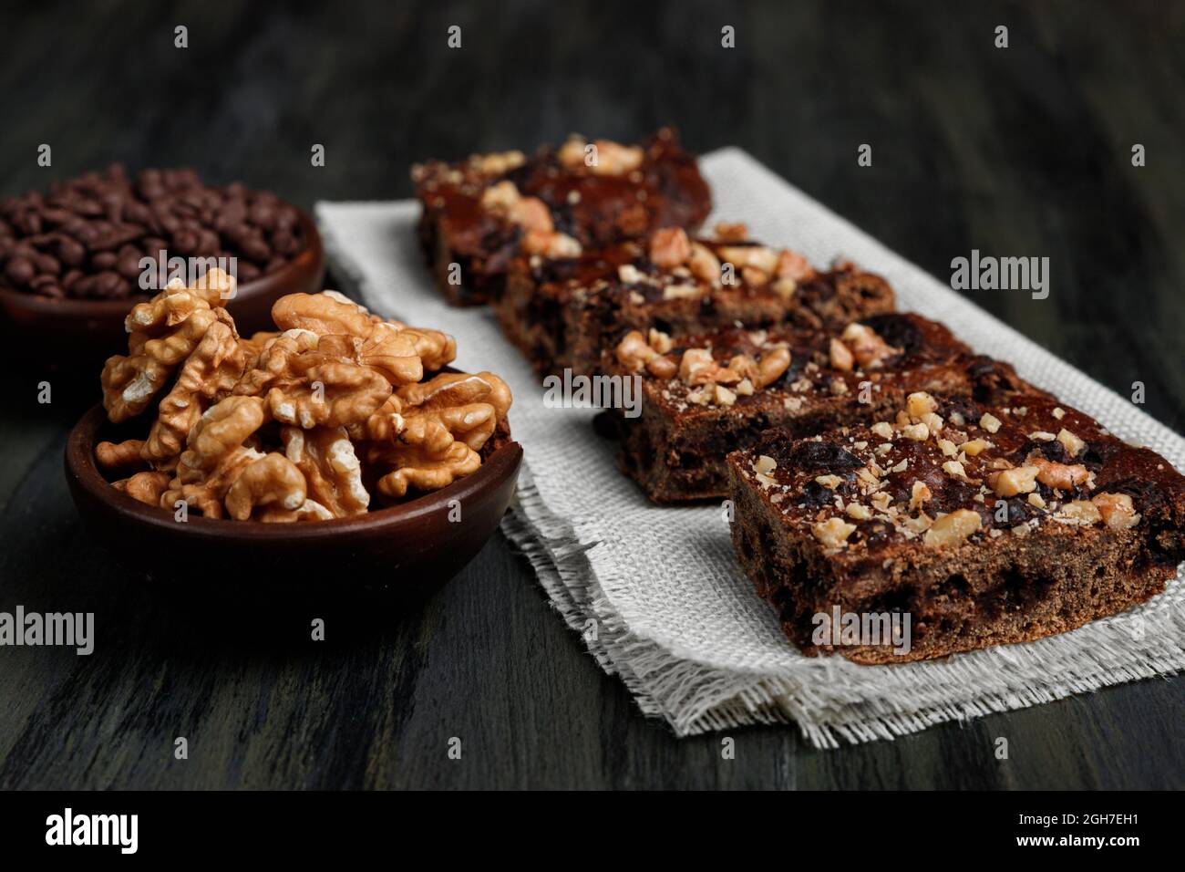 Schokoladenbrownie neben Walnüssen und Pralinen in Tontöpfen Stockfoto