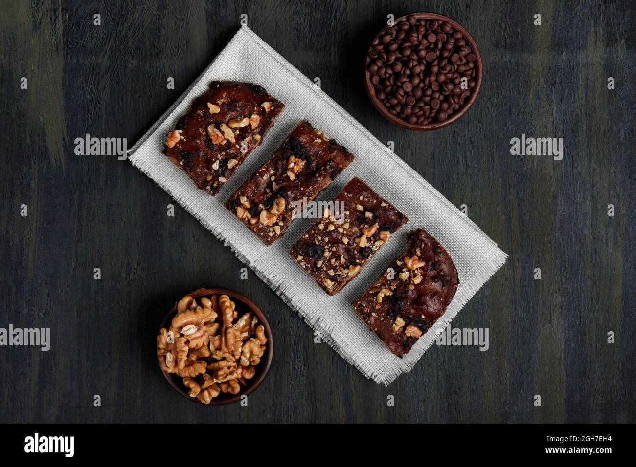 Schokoladenbrownie neben Walnüssen und Pralinen in Tontöpfen Stockfoto