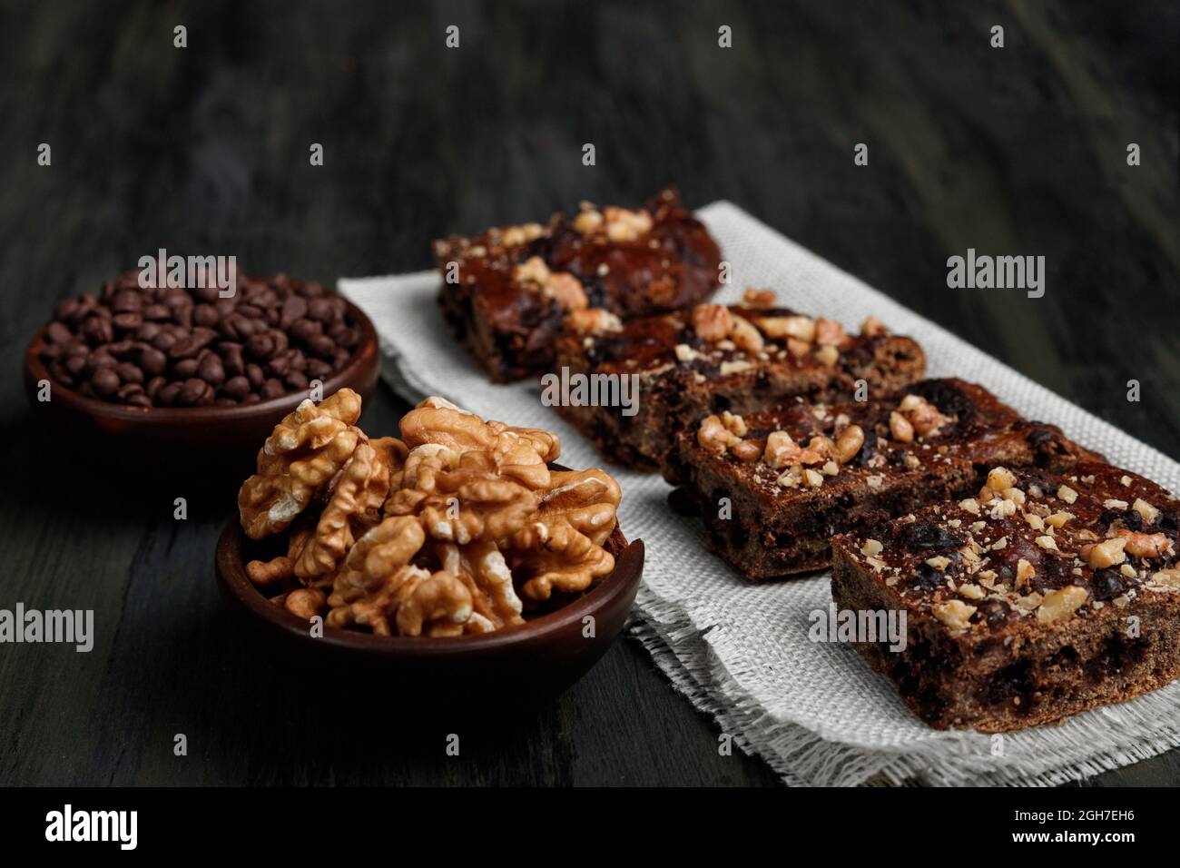 Schokoladenbrownie neben Walnüssen und Pralinen in Tontöpfen Stockfoto