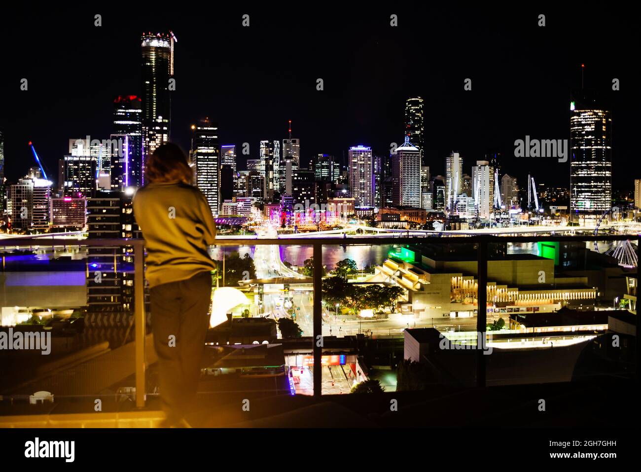 Junge Frau, die nachts auf die Stadt schaut Stockfoto
