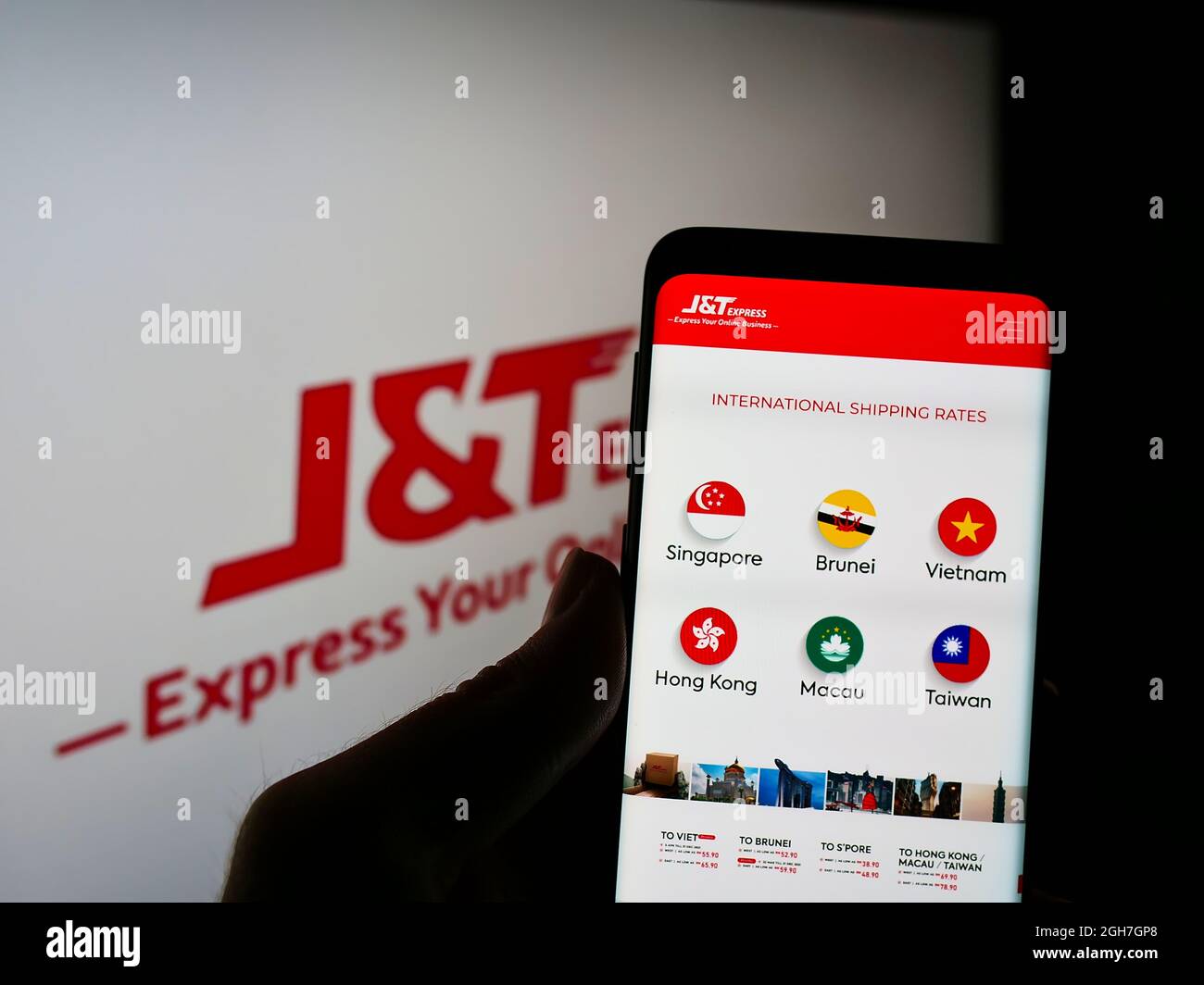 Person, die Smartphone mit Website des indonesischen Unternehmens PT Global Jet Express (JT) auf dem Bildschirm vor dem Unternehmenslogo hält. Konzentrieren Sie sich auf die Telefonanzeige. Stockfoto