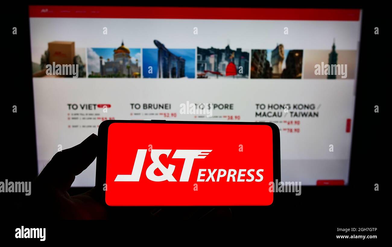 Person, die das Smartphone mit dem Logo des indonesischen Unternehmens PT Global Jet Express (JT) auf dem Bildschirm vor der Website hält. Konzentrieren Sie sich auf die Telefonanzeige. Stockfoto