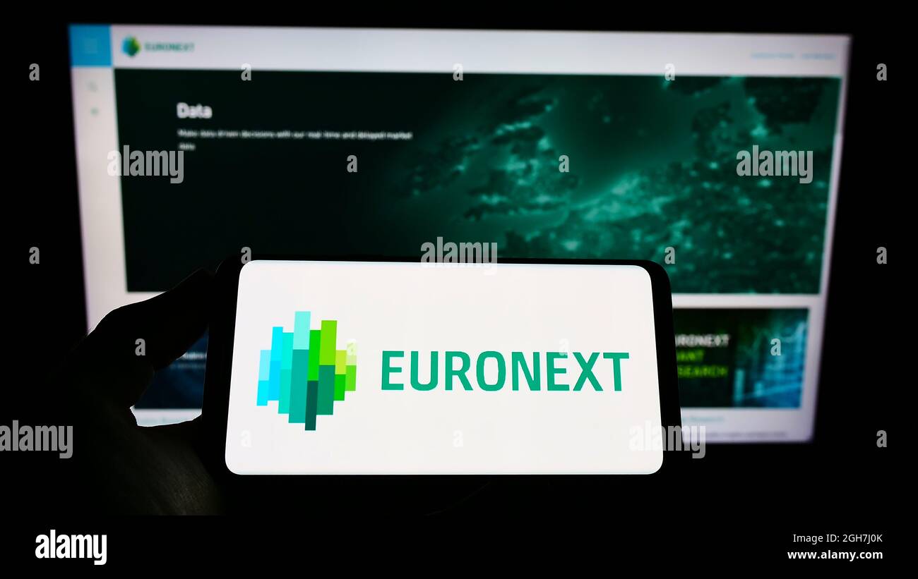 Person, die das Smartphone mit dem Logo des Finanzdienstleisters Euronext N.V. auf dem Bildschirm vor der Website hält. Konzentrieren Sie sich auf die Telefonanzeige. Stockfoto