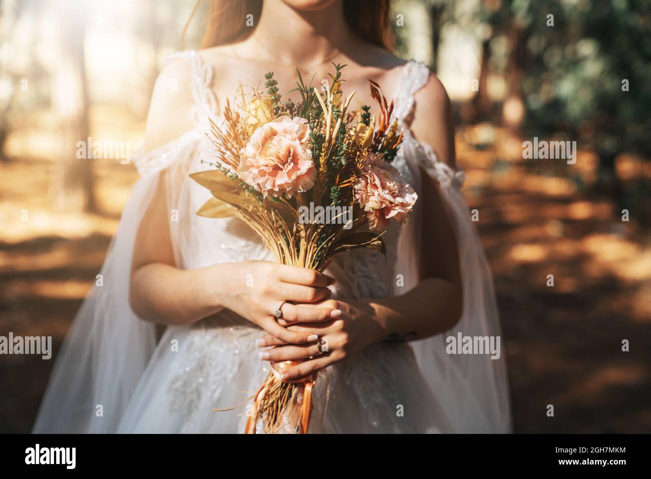 Braut mit weißem Hochzeitskleid im Wald hält bunte und getrocknete Hochzeit Bouquet. . Hochwertige Fotos Stockfoto