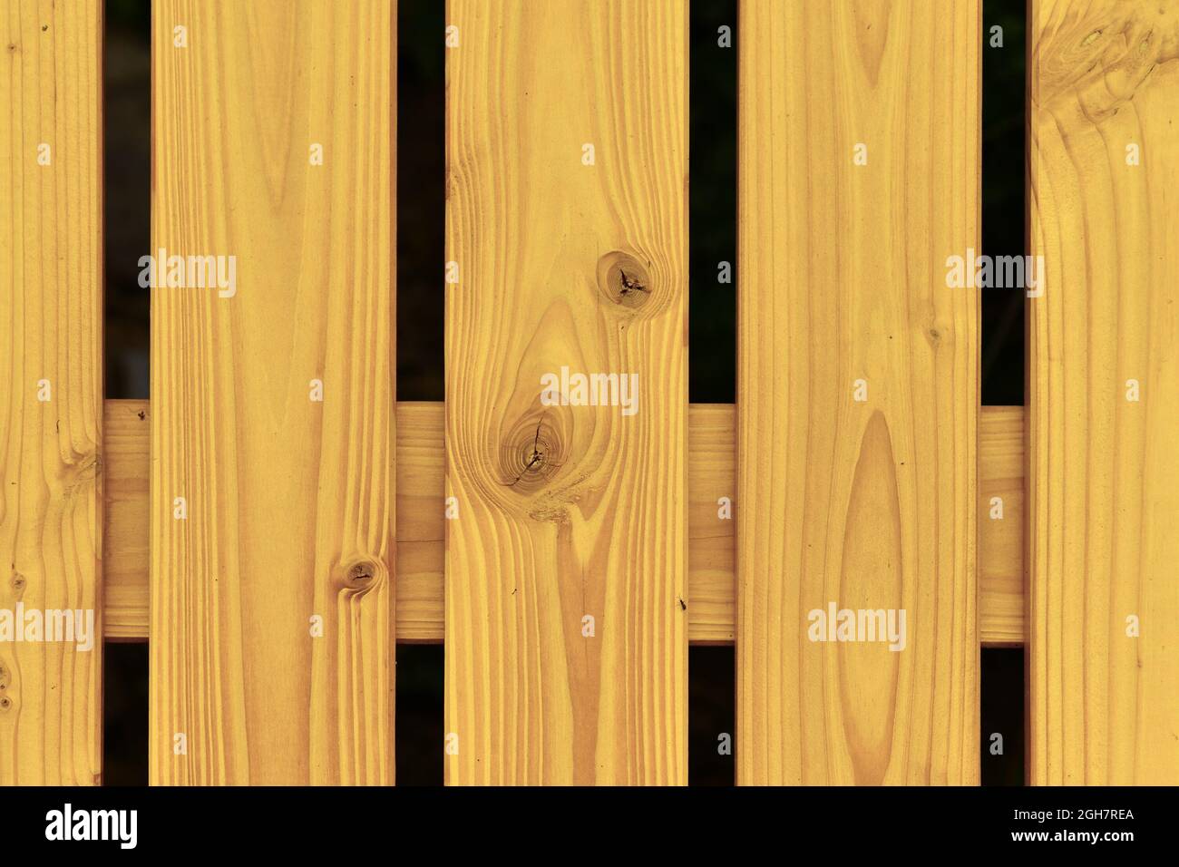 Gelb lackierte Holzbretter als Teil eines Zauns Stockfoto