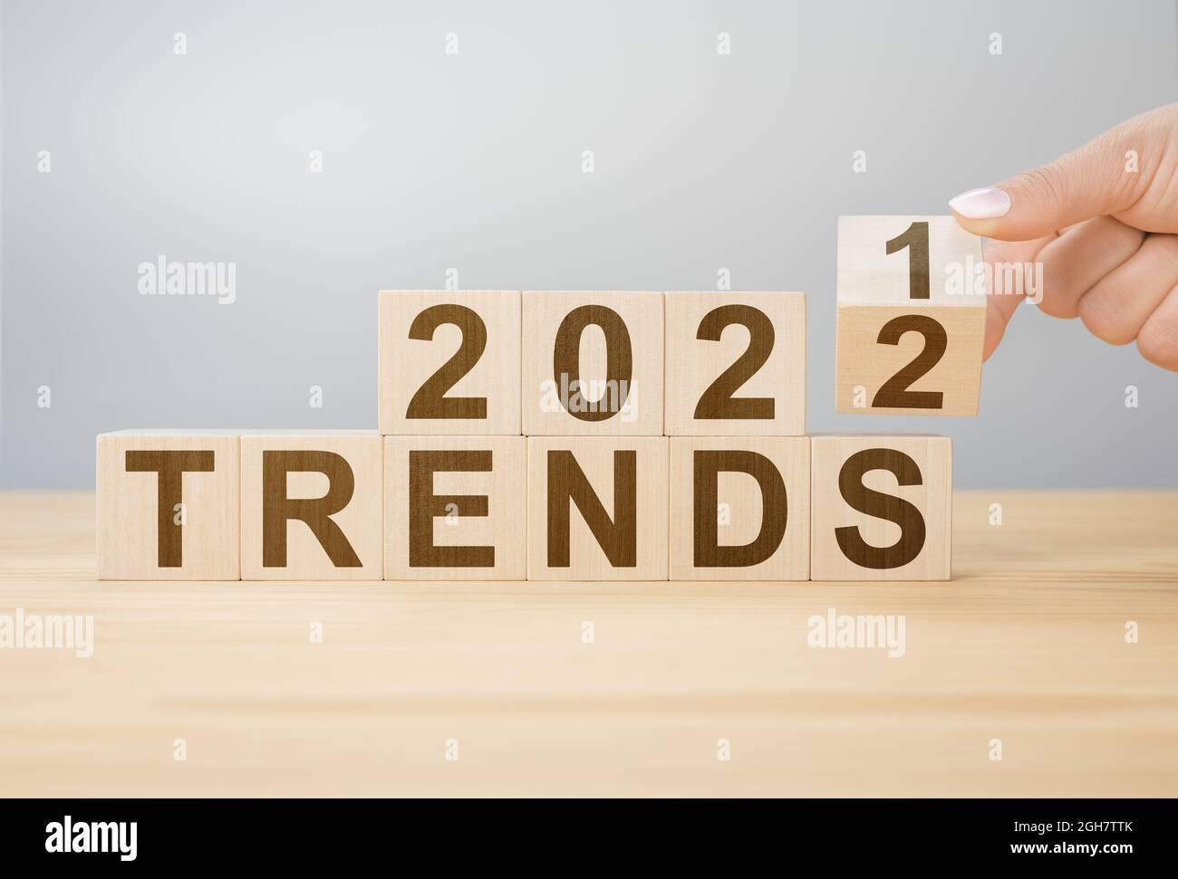 Trends 2022 Blocks. 2022 Trends Neujahr Symbol. Frau dreht einen Holzwürfel und ändert die Worte Trends 2021 zu Trends 2022. Drehen des hölzernen Würfelblocks Stockfoto