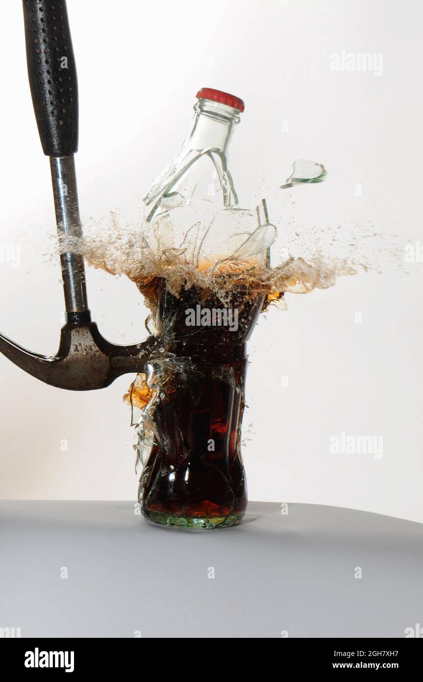 Stop Motion Hochgeschwindigkeitsfotografie eines Hammers, der eine Glas-Sodaflasche trifft und zerbricht Stockfoto