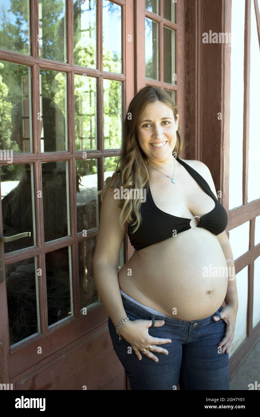 Sieben Monate schwanger junge Frau in schwarzem Bikini und Jeans gekleidet  Stockfotografie - Alamy