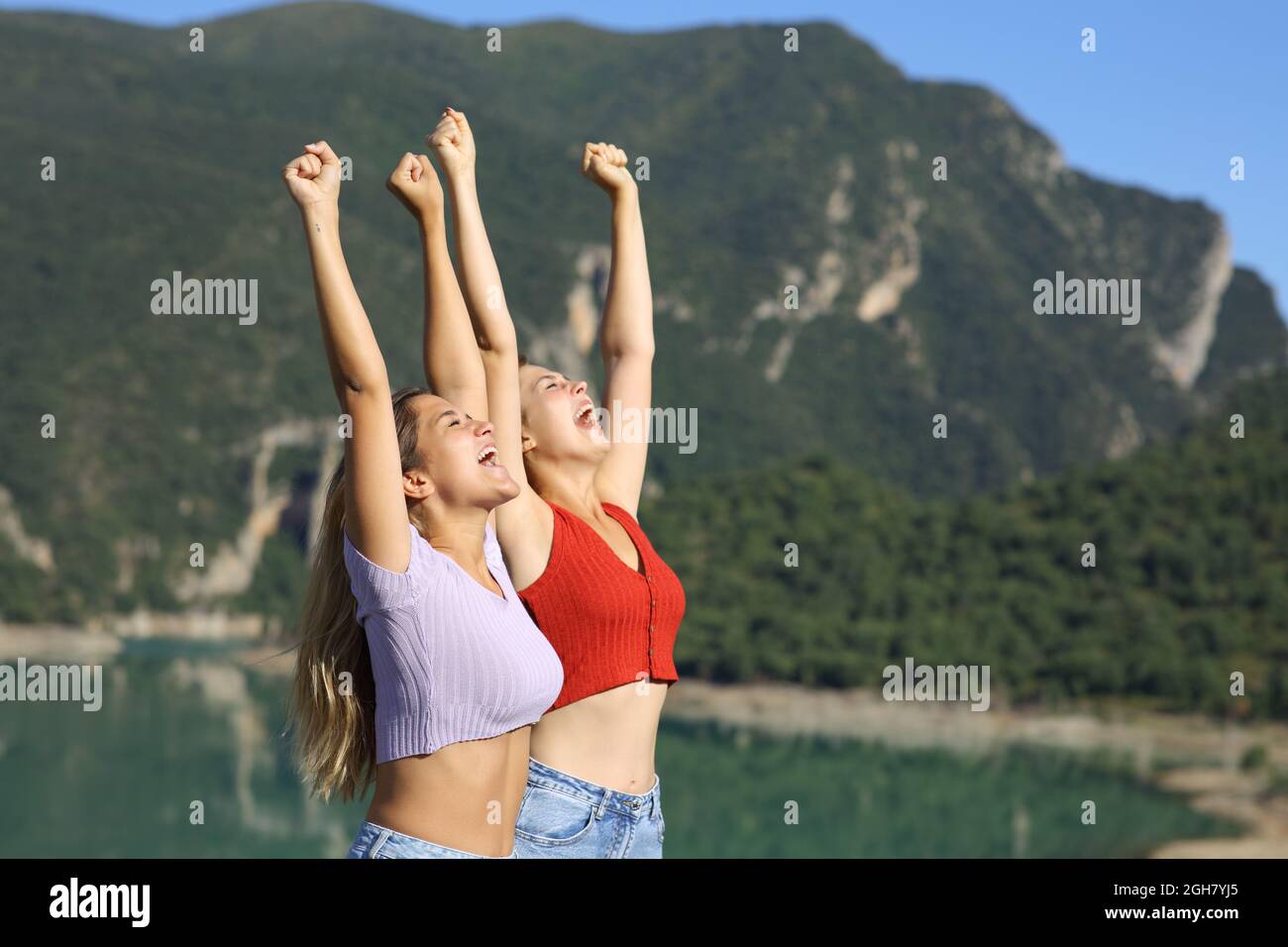 Zwei Frauen feiern Urlaub und heben sich im Sommer in der Natur die Arme Stockfoto
