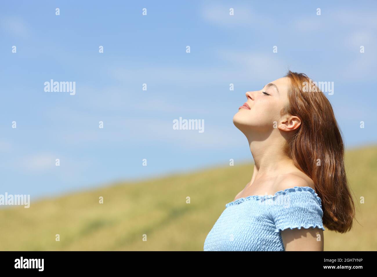 Profilportrait einer glücklichen Frau, die in einem Weizenfeld frische Luft atmet Stockfoto