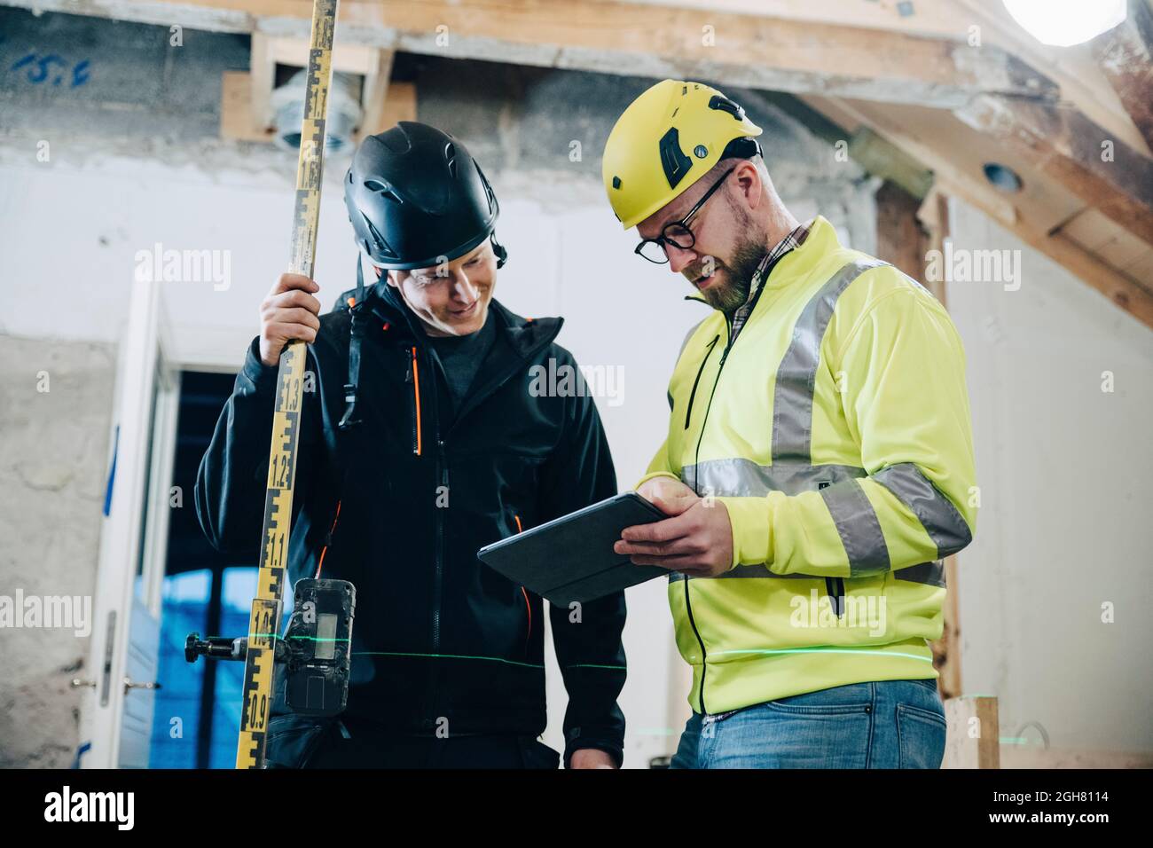 Männliche Bauarbeiter diskutieren während der Arbeit auf der Baustelle über digitale Tablets Stockfoto