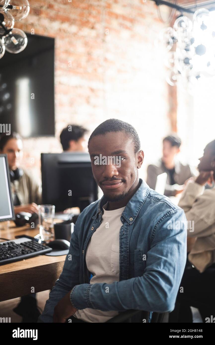 Porträt eines männlichen Hackers, der in einem Startup-Unternehmen sitzt Stockfoto