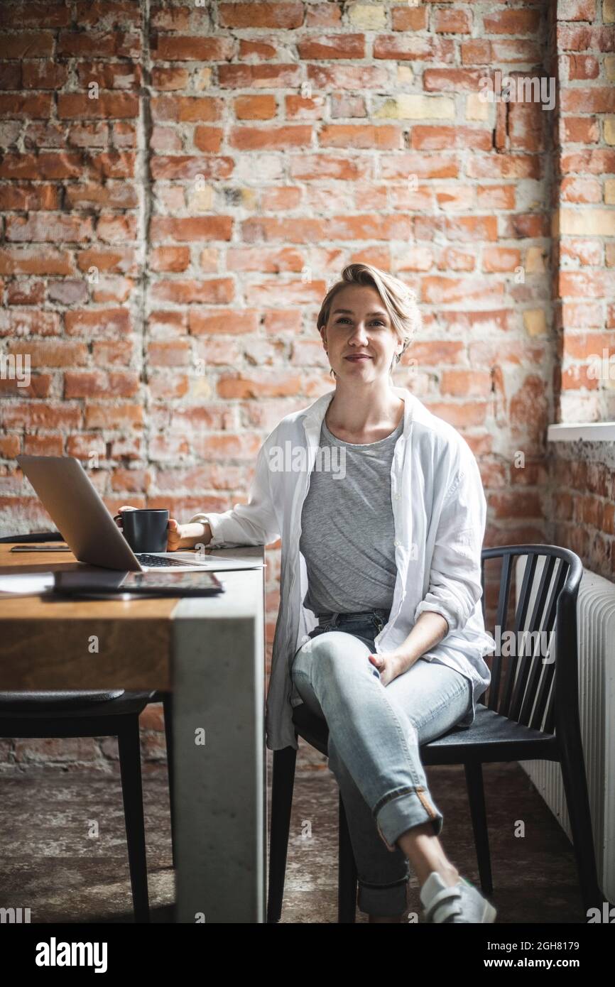 Porträt einer Hackerin, die im Büro auf einem Stuhl sitzt Stockfoto