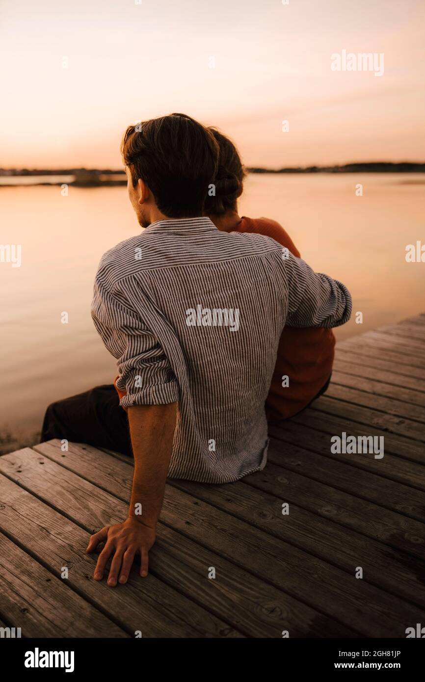 Mann, der Freizeit mit Freund verbringt, während er auf dem Pier sitzt Stockfoto