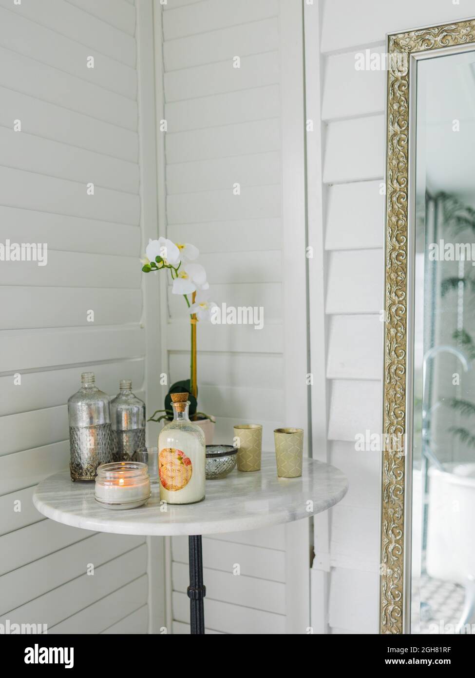 Kerzen und Orchideenblumen auf dem Tisch neben dem Spiegel im Badezimmer Stockfoto