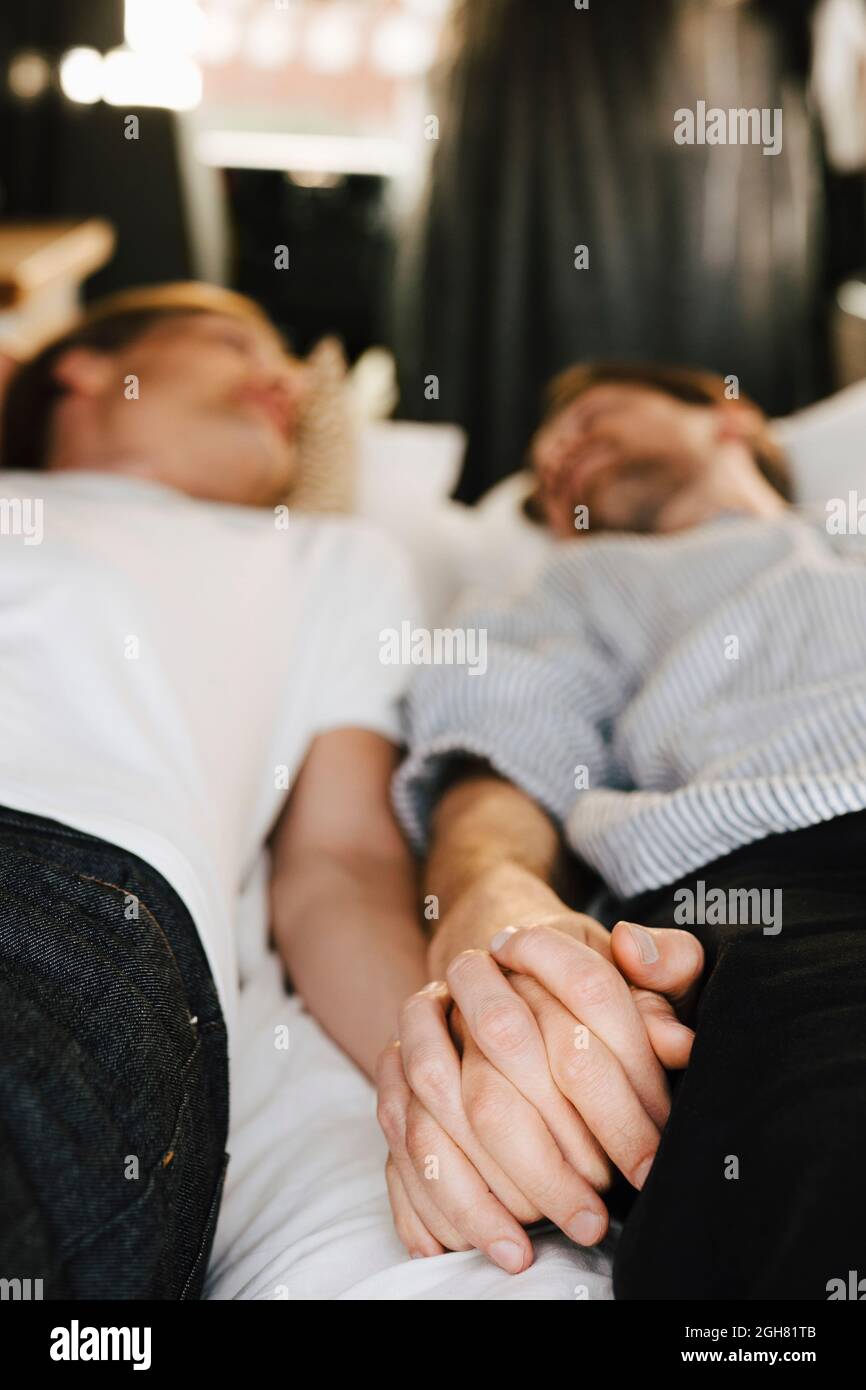 Schwule Paare halten sich die Hände, während sie im Urlaub im Wohnheim liegen Stockfoto