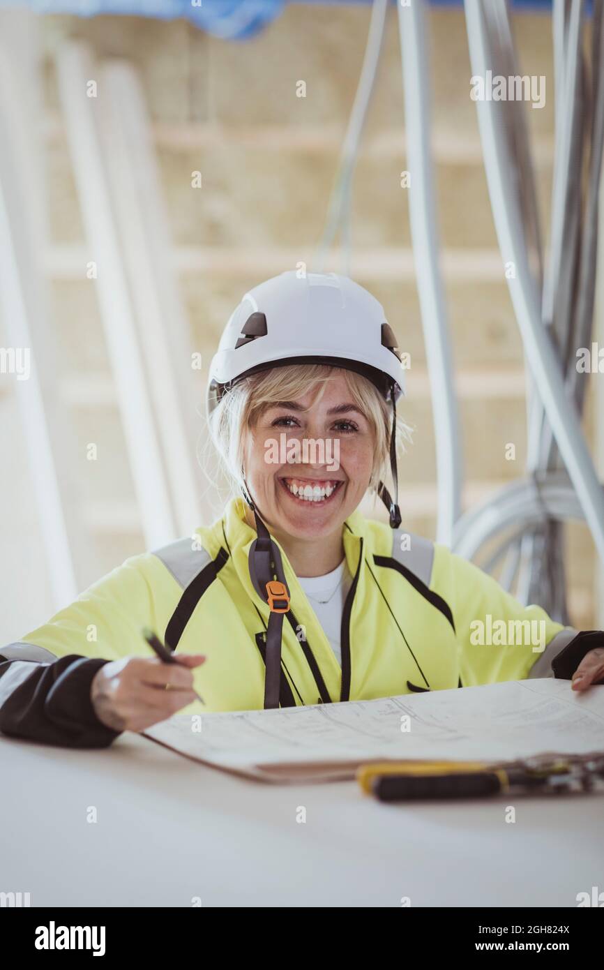 Porträt einer glücklichen Bauunternehmerin mit Grundriß auf der Baustelle Stockfoto