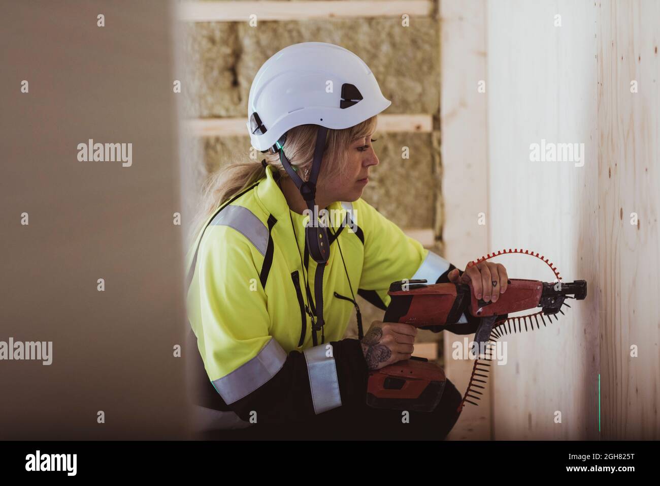 Bauherrin verwendet Arbeitswerkzeug an der Wand während der Arbeit auf der Baustelle Stockfoto
